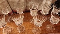 Ten Waterford stamped white wine glasses with clear cut crystal design on a wood surface, arranged in two rows