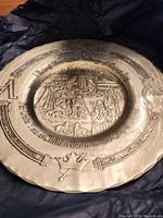 Top view of the Wendel August metal plate showing the embossed Nativity scene and inscriptions on a hammered metal surface.