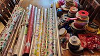 Wide view of all wrapping paper rolls and ribbons laid out on table showing various patterns and types.