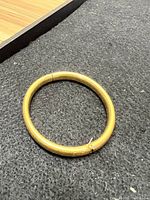 Photo of round 14K gold bangle bracelet with resin core on black carpeted surface.
