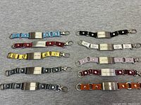 All eight motivational bracelets laid out in two rows showing colored leather straps and metal plates.