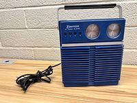 Frontal image showing the blue Emerson eight track player with handle and attached power cord.