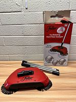 Red Fuller Rotating Hard Floor Sweeper base shown assembled with brushes visible, next to the original box showing product details.