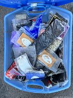 Top view of large blue plastic tub filled with sealed packages of various Magic Touch braid hair extensions in assorted colors and textures.