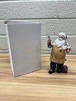 Photo of the Santa Claus figurine standing next to the original white Lenox box with gold lettering.
