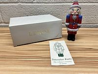 Nutcracker Santa figurine standing next to original white box and pamphlet