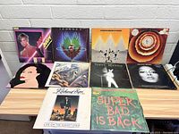 Photo showing all 10 vinyl records arranged on a table with various cover artwork.