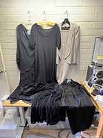 Lot of five women's dresses hung and laid on a table showing overall condition and different styles.