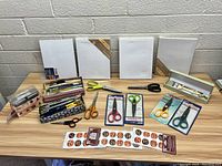 Full layout of canvases, scissors, tins with brushes and stickers on a table