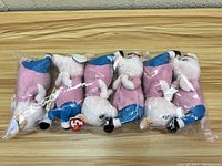 Six Ty Beanie Babies pigs from Sing in a clear plastic bag, side view showing poses and outfits.
