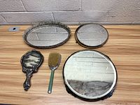 Four vintage mirrors on table with variety of shapes and metal frames.