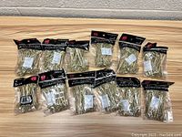 Twelve packages of bamboo flower knot picks in black-top bags with white text, arranged on a wooden surface showing quantity and packaging.