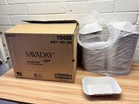 Opened cardboard box labeled Savaday by Chinet containing 500 molded fiber white trays, with a single tray placed in front to show size and shape.
