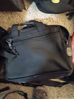 Single black nylon briefcase or laptop bag with handles and shoulder strap lying on carpet