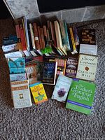 Books arranged standing and stacked on carpet, showing array of fiction and non-fiction titles