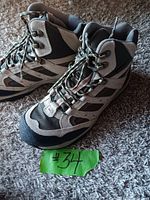 Pair of gray and black LLBean hiking boots with green and black laces shown from side on a carpeted floor.