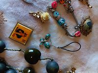 Close-up of various costume jewelry items including bracelets with colorful beads and rings with green stones.