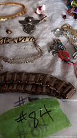 Variety of costume jewelry pieces including chains, bracelets, pins, and rings arranged on a white surface.