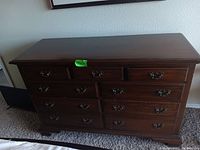 Front view of wood dresser showing all drawers and handles, highlighting condition with minor corner damage.