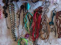 Photo of assorted costume jewelry featuring various necklaces, bracelets, rings, and earrings spread on fabric background.