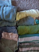 Photo showing a stack of assorted bath towels in colors including light blue, yellow, green, gray, pink, and white with stripes.