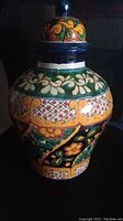 Colorful large Mexican pottery vase with lid featuring multi-color hand-painted floral and geometric patterns.