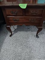 Front view of wooden night stand showing two top small drawers and two larger bottom drawers with ornate metal handles and cabriole legs.