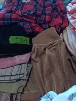 Photo showing red and purple plaid pajama top with beige velour bottoms nearby, and black pajama bottoms tagged #33 underneath.