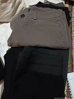 Folded pants in gray and black colors showing button and pocket details