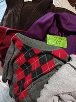 Top view of sweaters showing black, purple velvet, argyle pattern, and other textured knit sweaters grouped together