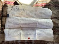 Photo of large antique English indenture lease document on patterned fabric background, showing full document with text and signature