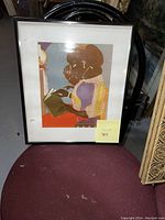 Front view of the framed art print sitting on a chair, showing the artwork depicting two women.