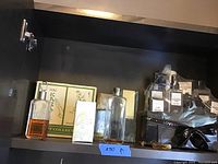 Shelf with various vintage cologne bottles and gift sets including Lowery, Lauder and Lagerfeld bottles with amber liquid, and boxed items.