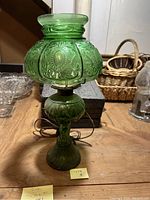 Full view of the green glass lamp showing ornate glass shade and base with electrical cord.