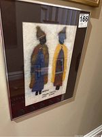 Framed embroidered fleece artwork featuring two figures in traditional attire.