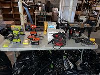 Wide view of all power tools on table including drills, compressor, router, steamer