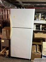 Closed white textured Frigidaire refrigerator in basement setting.