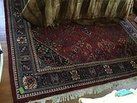Photo of red oriental area rug showing large size and pattern beneath sofa.