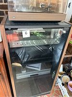 Full view of glass-door cabinet containing receiver, CD changer, VHS/DVD player