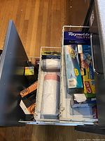 Drawer with assorted kitchen wrap products including Reynolds plastic coated freezer paper, plastic wrap, Glad bags, Hefty slider bags, and other boxed items.