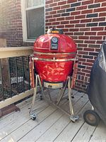 Full front view of red ceramic grill on stainless steel rolling base