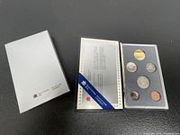 Set of six Canadian coins in clear plastic display case with black foam insert and original packaging including informational insert and outer box.