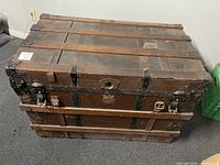 Front and top view of antique wooden chest showing metal bands, latch, keyhole, and missing handles
