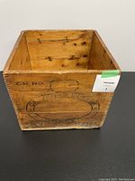 Image of one side of the wooden crate showing faded branding and stamps including 'CH NO' with an oval butter mold print.