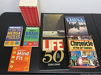 Full view of seven books including puzzle books, Life anniversary volume, and Chronicle.