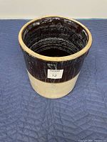 Stoneware crock with dark brown upper glaze and natural beige lower portion, round open top, viewed from above