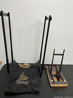 Metal firewood rack with fabric carrying sling and manual log splitter next to it.