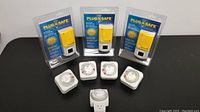 Photo showing three new Plug & Safe yellow sensor devices in packaging and five white dial-type light timers, one specifically identified as aquarium light timer.