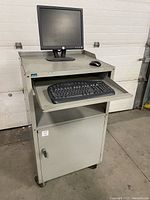 Front view of portable computer station with monitor, keyboard on pull-out tray, and mouse on top surface