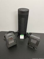 Photo of a black Honeywell oscillating tower space heater, 22 inches tall, with illuminated digital control panel on top, alongside two smaller black box heaters with grille fronts and rotary dial controls.